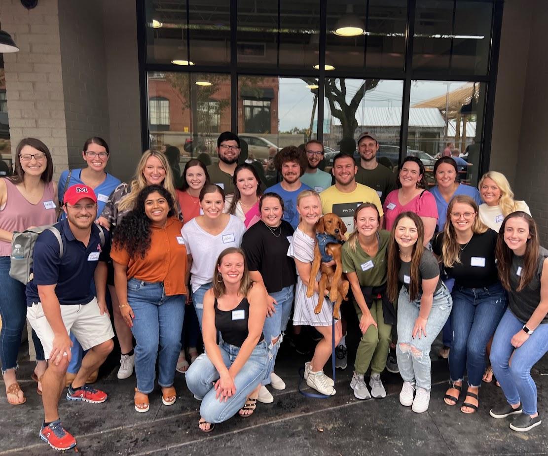 group picture of 23 pediatric residents while one of them holds up a service dog